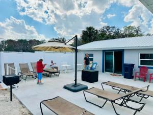 Dos personas de pie en un patio con una sombrilla. en Cottage 23, The Lighthouse - Dora Canal Court - a downtown, waterfront community, en Tavares