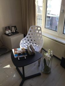 uma cadeira branca sentada numa sala de estar com uma mesa em France Hotel em Amsterdã