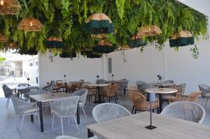 a dining room with tables and chairs and plants at Astra Beach Club & Resort in Marcelino