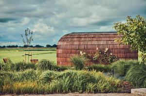 a barn in the middle of a field with grass at Nest - luxe wellness met privé sauna in Friesland in Luxwoude