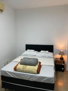 a bedroom with a large bed with white sheets at Apto no centro da cidade mais alemã do Brasil in Pomerode