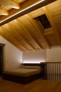 - une chambre avec un lit et des plafonds en bois dans l'établissement Ca' Palmina - Appartamento con soppalco, à Ardenno