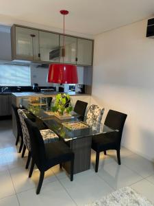 a dining room with a glass table and black chairs at Apto no centro da cidade mais alemã do Brasil in Pomerode