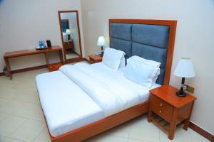 a bedroom with a large bed with a blue headboard at Rostel Villa Hotel in Mbeya