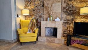 a yellow chair in a living room with a fireplace at Stone Rustic Beach apartment in Blanes
