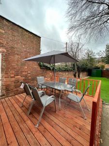 a table and chairs with an umbrella on a wooden deck at Regent Cosy in Coventry
