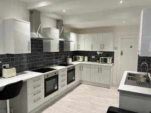 a large kitchen with white cabinets and appliances at Regent Cosy in Coventry