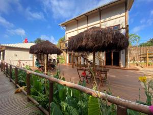 a building with a deck with chairs and straw umbrellas at Vila Cris in Fernando de Noronha