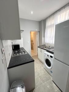 a kitchen with a stove and a washing machine at One Bedroom Apartment Near Heathrow Airport & London in Hayes