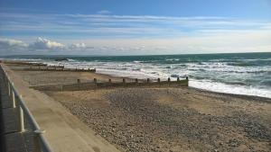 a beach with a wooden fence and the ocean at Chalet 7 Erw Porthor in Tywyn