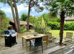 una terrazza in legno con tavolo, sedie e griglia di Ideal house for family vacations, peaceful setting a Lège-Cap-Ferret