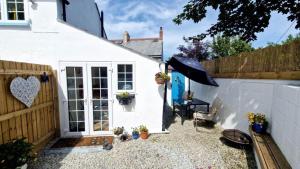 una casa bianca con un ombrello e una recinzione di North Cornwall 2-Bed Detached Period Cottage With Parking a Camelford