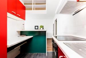 ケルンにあるFair Apartments Cologneのキッチン(赤と緑のキャビネット、シンク付)
