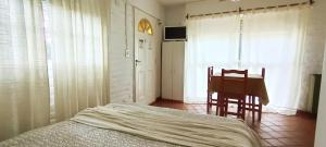 a bedroom with a bed and a desk and a table at Tiny House Las Violetas en Villa Serrana La Gruta in San Andres de las Sierras