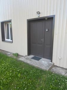 un garage con una porta nera accanto a un edificio di Straume a Valmiera
