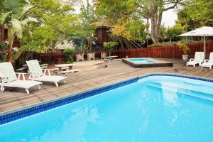 a swimming pool with a wooden deck and chairs and a swimming pool at Knysna Retreat - Knysna River Club in Knysna