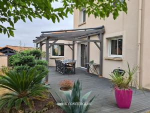 a patio with a table and a pergola at Chez Caco maison lumineuse avec jardin proche du Puy duFou in Les Herbiers