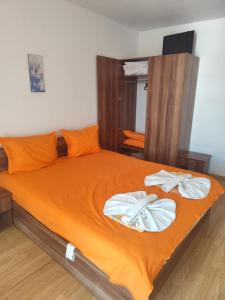 a bedroom with a bed with orange sheets and towels at Dima Popova Apartments in Tsarevo