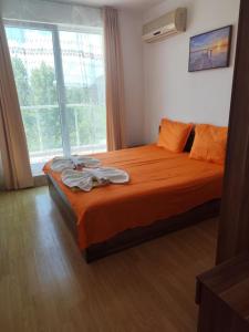 a bedroom with a bed with orange sheets and a window at Dima Popova Apartments in Tsarevo +192 photos