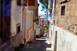 an alley with buildings and a car on a street at Kelebek Butik Pansiyon in Ayvalık