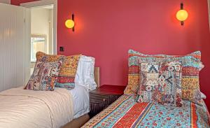 a bedroom with red walls and a bed and pillows at LUTON LUXURY LIVING, Large PREMIUM House, Beautifully Landscaped PRIVATE GARDEN, Newly Refurbished Throughout, PARKING FOR 2 VEHICLES, Great Access to Central Luton & the M1 Motorway in Luton