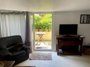 ein Wohnzimmer mit Sofa und Fernseher in der Unterkunft Logement 30m de la mer! dans maison in Hermanville-sur-Mer