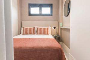 a small bedroom with a bed with orange sheets and a window at Picasso III in Málaga
