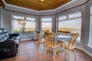 a dining room with a table and chairs and a couch at Shoreline Cottage in Rosapenna
