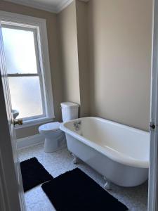 une salle de bain avec baignoire et toilettes et une fenêtre dans l'établissement St Johns spacious Heritage Stay est 1901, à Saint-Jean 38 autres photos