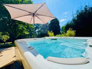 a hot tub with an umbrella and a chair at Domaine du Mafay - LODGE PROVENÇALE in Bourg-des-Comptes