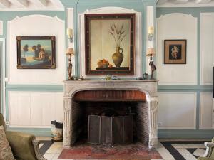 una sala de estar con chimenea y una pintura en la pared en Le Manoir de la Seine - proche Giverny, en Bennecourt