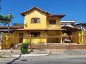 a yellow house with a fence in front of it at Pousada Jardim Alterosa in Vespasiano