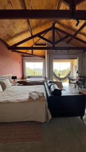 a bedroom with a large bed in a room with windows at Quinta da Serra Villa & Chalés in Santo Antônio do Pinhal