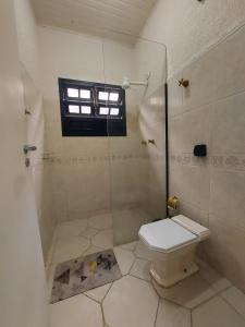 a bathroom with a toilet and a shower with a window at Cantinho Da Go in Caraguatatuba