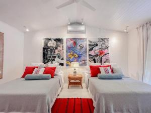 two beds in a room with paintings on the wall at Casa Agog - Retreat Spacepoolsteps To Beach in Puerto Viejo +50 photos