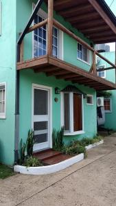 a green house with a balcony on top of it at Complejo Rio Azul in La Porteña