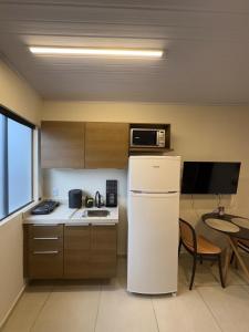 a kitchen with a white refrigerator and a table at Flat 03 Tudo novo e bem equipado - Terra das Águas in Bonito