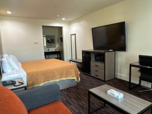 ケイティーにあるScottish Inn and Suitesのベッドと薄型テレビがあるホテルの部屋
