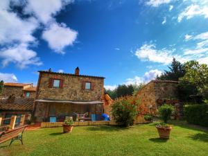 a large stone house with a yard with a bench at Farmhouse in Castiglione Dorcia in San Quirico dʼOrcia