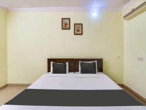 a bedroom with a large white bed with two pillows at Hotel O SS ELITE in Karīmnagar +21 photos