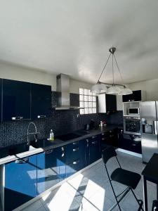 a large kitchen with blue cabinets and a sink at Villa à 30 min des parcs Asterix et Disneyland in Chelles
