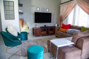 Una sala de estar con un sofá y sillas y un televisor. en LUXE 25 On Eagle, en Vosburg