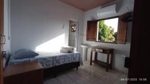 a small bedroom with a bed and a window at Pouso do Sol in Pirenópolis