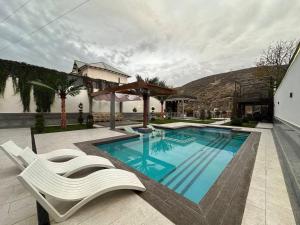 a swimming pool with two chairs next to a building at Villa Lux I in Chorwoq