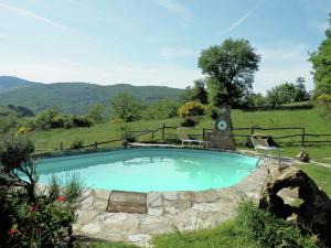 a swimming pool in a field with mountains in the background at Striking Farmhouse, Ortignano in Castel Focognano