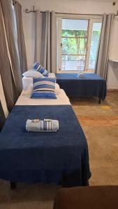 a bedroom with two beds with blue sheets and a window at Casas Loft Búzios in Búzios