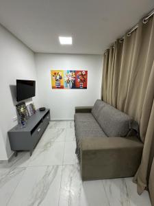 a living room with a couch and a tv at Condominio HOME DUPLEX SERRA NEGRA in Bezerros