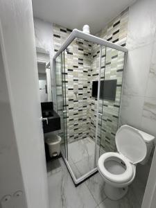 a bathroom with a toilet and a glass shower at Condominio HOME DUPLEX SERRA NEGRA in Bezerros