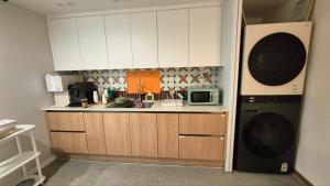 a kitchen with white cabinets and a microwave at Bom Stay in Seoul +7 photos