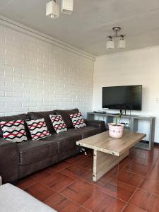a living room with a couch and a tv at Casa Hostal Nora, Rauquén Curicó in Curicó
